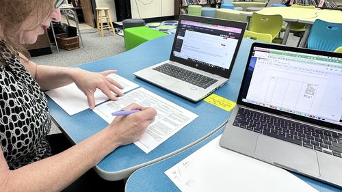 Contextual inquiry: a teacher reviewing paper materials beside a laptop